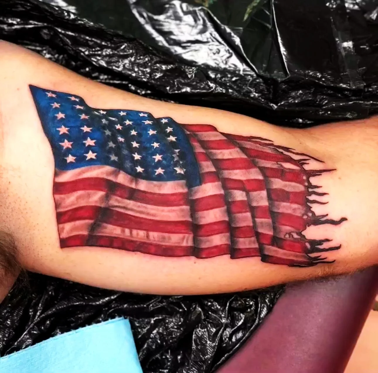 Color Realism tattered American flag tattoo on bicep by 2bit (Chris Curren) at Lost at Sea Tattoo, Chinatown, Honolulu Color Realism tattered American flag tattoo on bicep by 2bit (Chris Curren) at Lost at Sea Tattoo, Chinatown, Honolulu